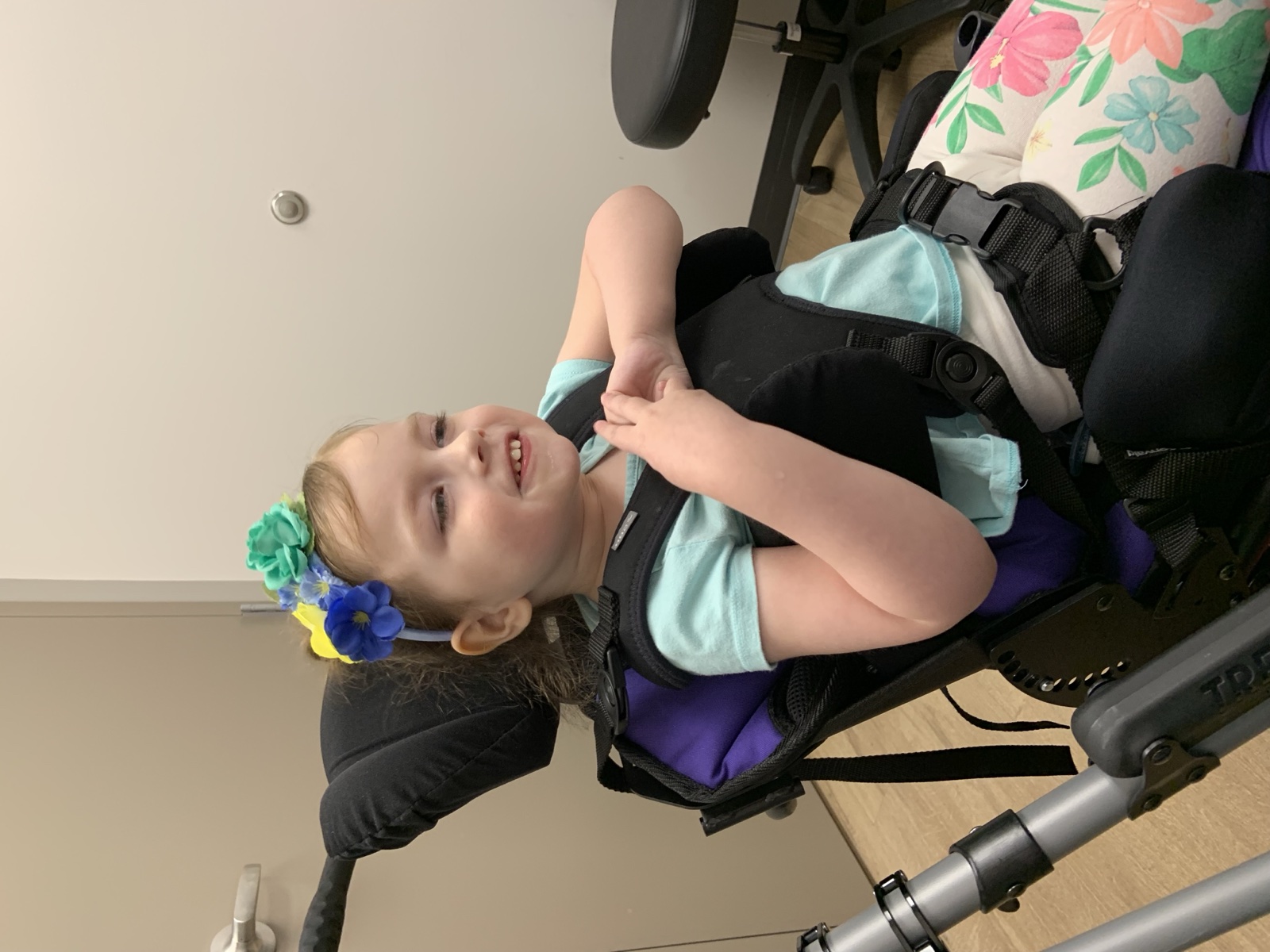 Sophia smiling in her wheelchair with flowers in her hair in 2019