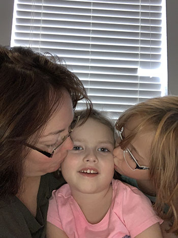 Sophia being kissed by her mother and sister