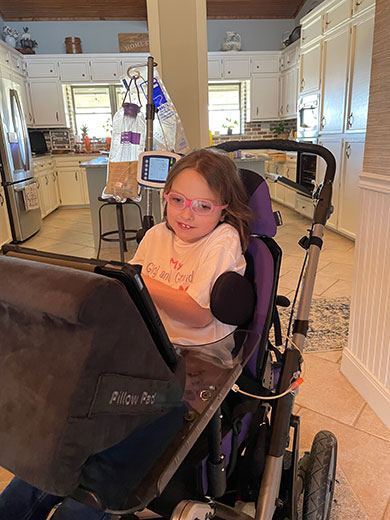 Sophia smiling in her wheelchair at home